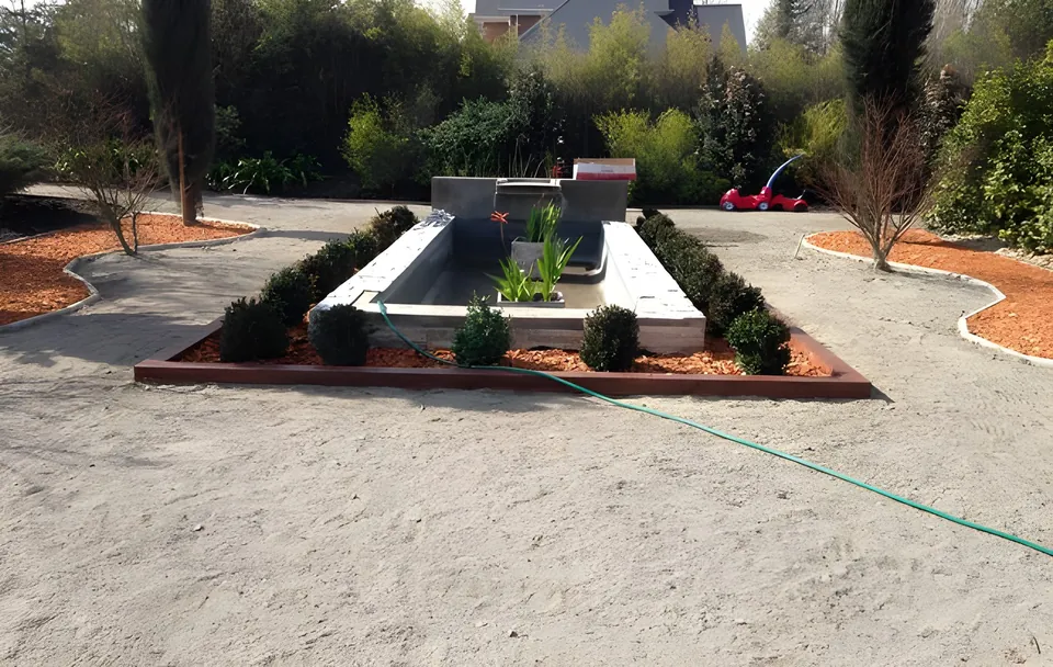 Plaza con espejo de agua y jardineras con bordes de mulch naranjo