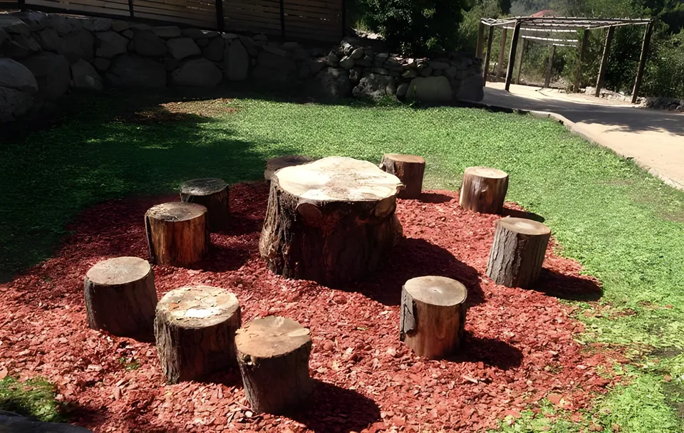Plaza con asientos de tronco sobre mulch rojo